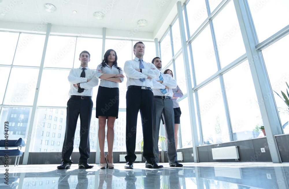 Smiling and confident business team standing in front of a bright Smiling and confident business team standing in front of a bright