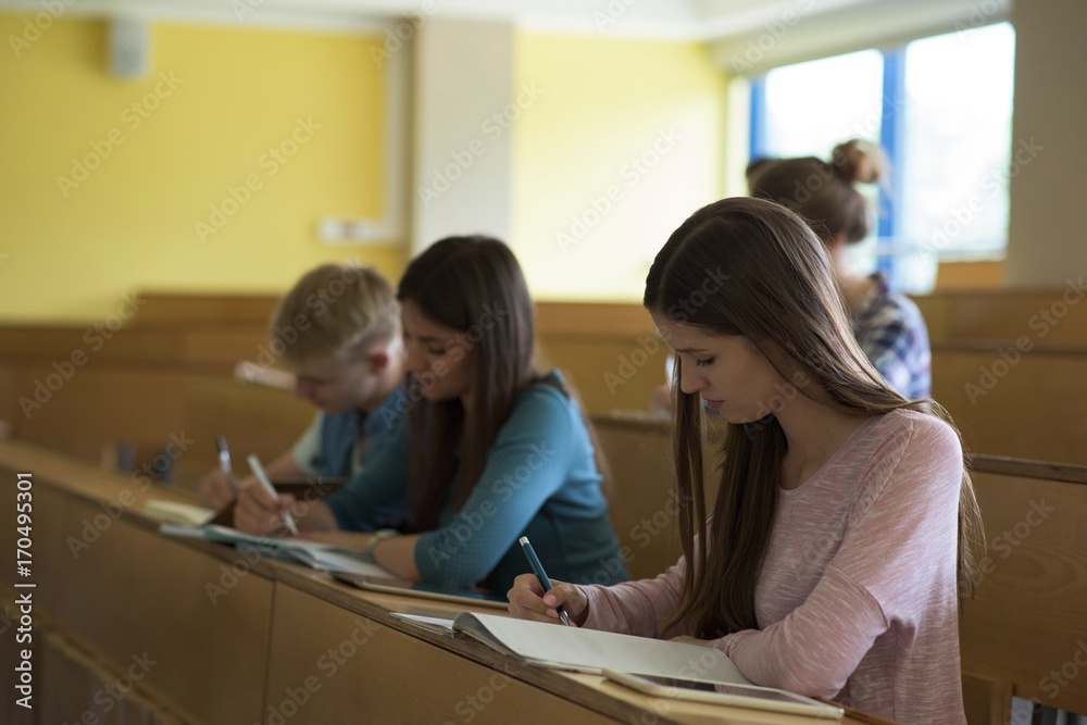 Young college students writing on book at desk Young college students writing on book at desk