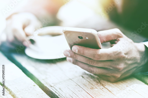 businessman hand holding morning coffee and reading tphone photo