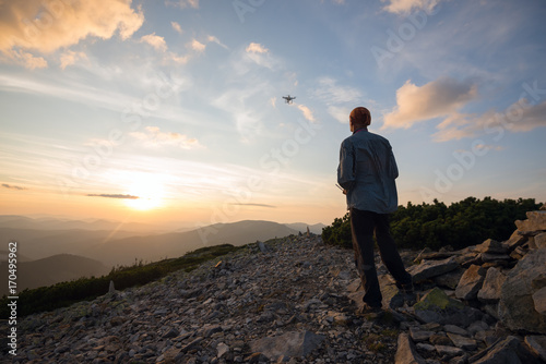 Traveler stands in the mountains and controls the drone