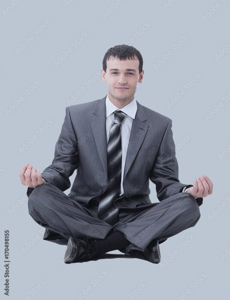 Calm businessman sitting in lotus pose on gray background Calm businessman sitting in lotus pose on gray background