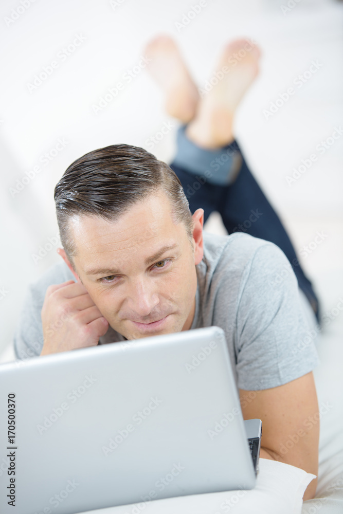 smiling man using laptop in a bed