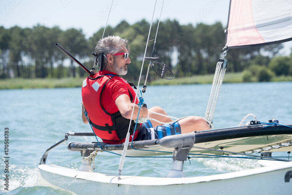 Naklejka premium man sailing with sails out on a sunny day