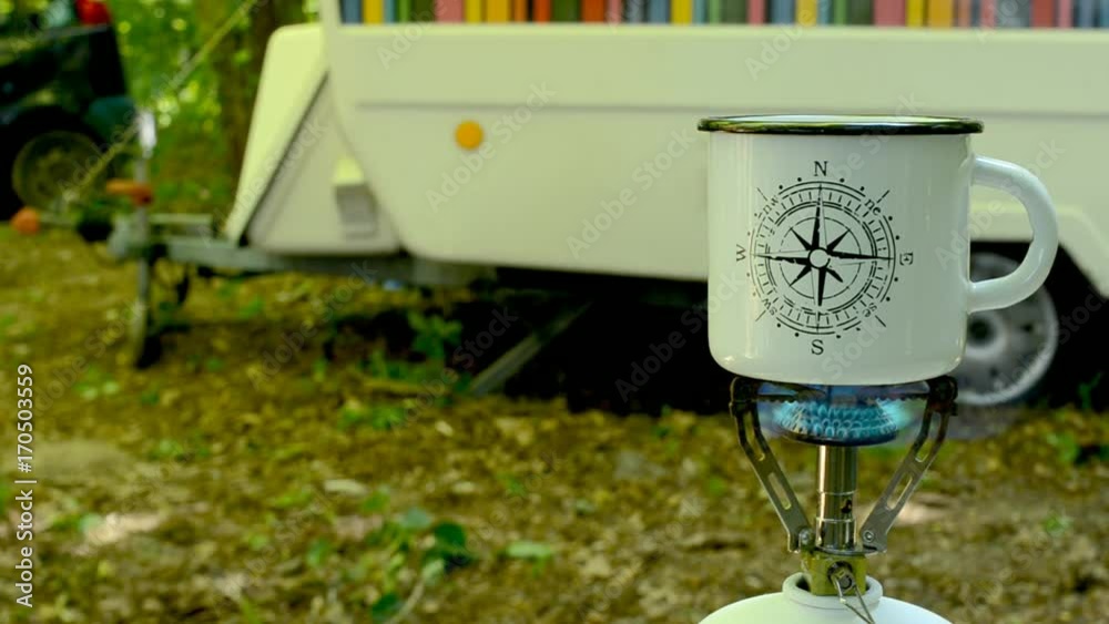 A traveler is brewing coffee in a forest. A traveler is brewing coffee in a forest.