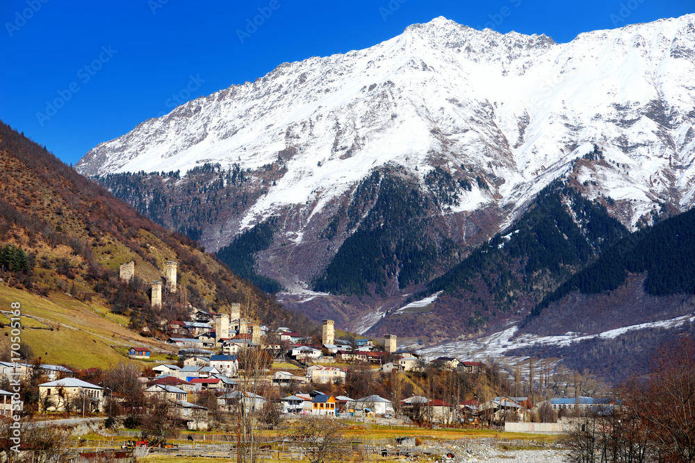 Breathtaking view of medieval Mestia village dotted with famous Svaneti towers on chilly sunny day in late autumn