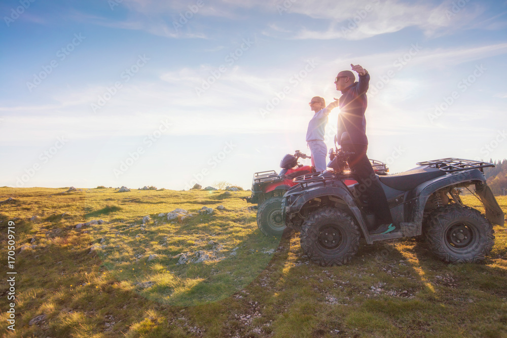 Rear view of young pair near atv. Man is showing something in distance to her girlfriend. Rear view of young pair near atv. Man is showing something in distance to her girlfriend.