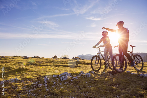 Fototapeta Naklejka Na Ścianę i Meble -  Biker couple with mountain bike pointing in distance at countryside