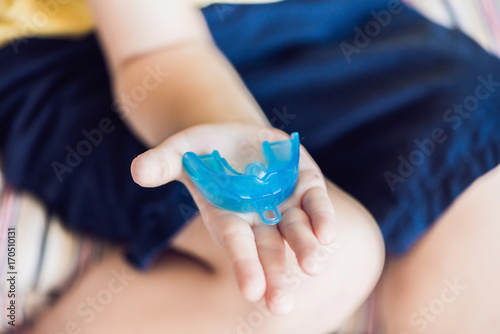 Three-year old boy shows myofunctional trainer to illuminate mouth breathing habit. Helps equalize the growing teeth and correct bite. Corrects the position of the tongue photo