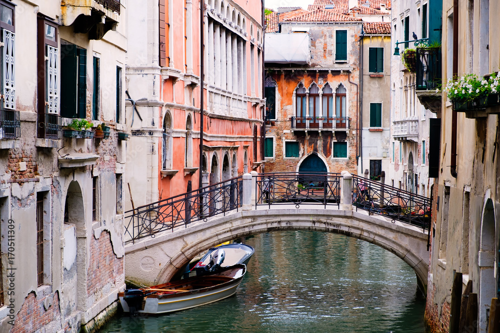 Bridge over a narrow canal sidelined by old buildings in Venice