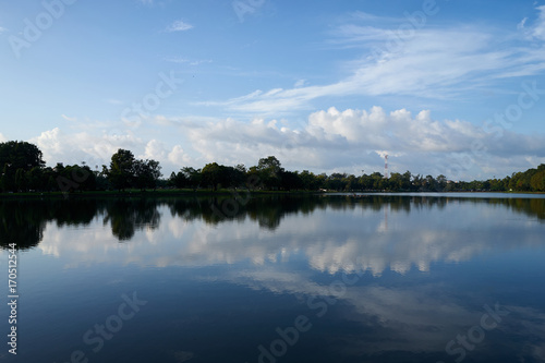 white cloudy blue sky at public park nearly the town with reflection on water