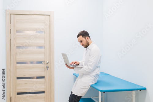 specialist doctor in the corridor of his clinic with his laptop