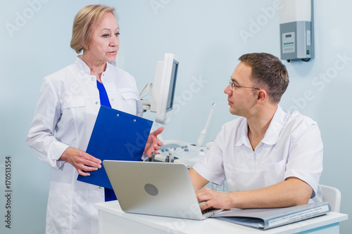 Doctor having conversation with his colleague and holding xray in medical office