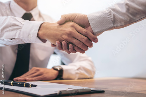 Estate broker agent and customer shaking hands after signing contract documents for realty purchase mortgage loan approval photo