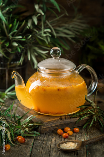 hot  tea with sea buckthorn in glass teapot photo