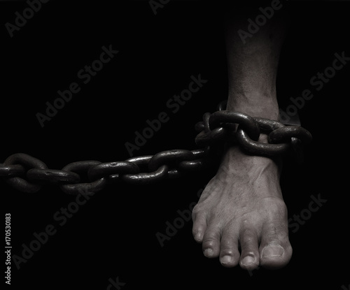 Victim, Slave, Prisoner male foor tied by big metal chain. People have no freedom concept image.