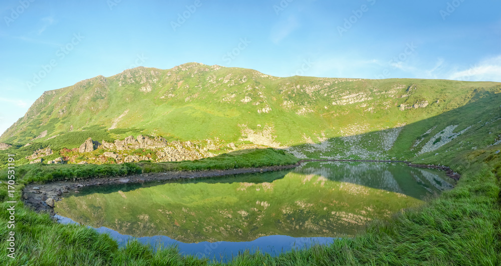 Obraz premium Mountain lake and mountain slope reflected in it