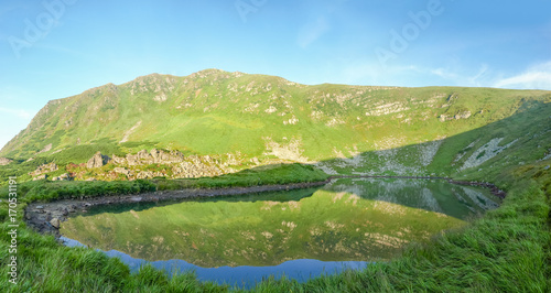 Mountain lake and mountain slope reflected in it