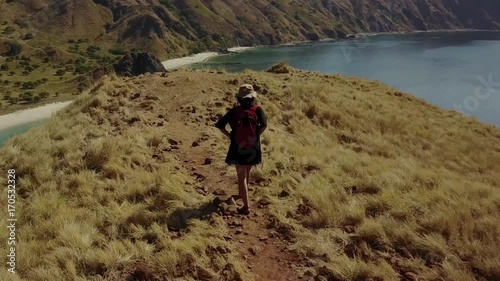 Beautiful aerial view footage of a female hiker walking on the Padar Island hill while carrying bag in East Nusa Tenggara, Indonesia. photo