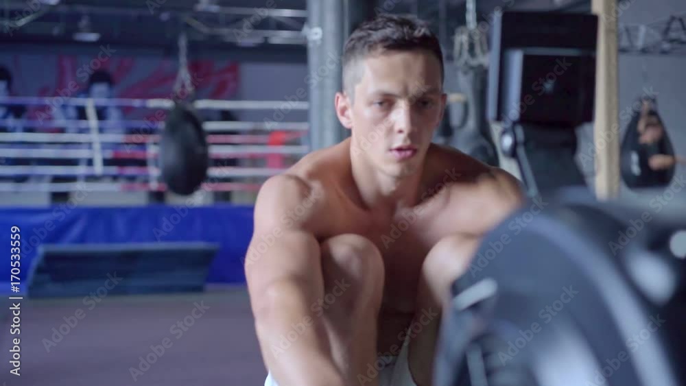 Young athletic man doing rowing machine workout at the gym Young athletic man doing rowing machine workout at the gym