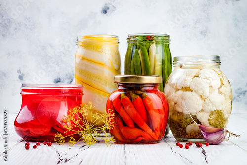 Marinated pickles variety preserving jars. Homemade green beans, squash, radish, red chili peppers, cauliflower pickles. Fermented food.