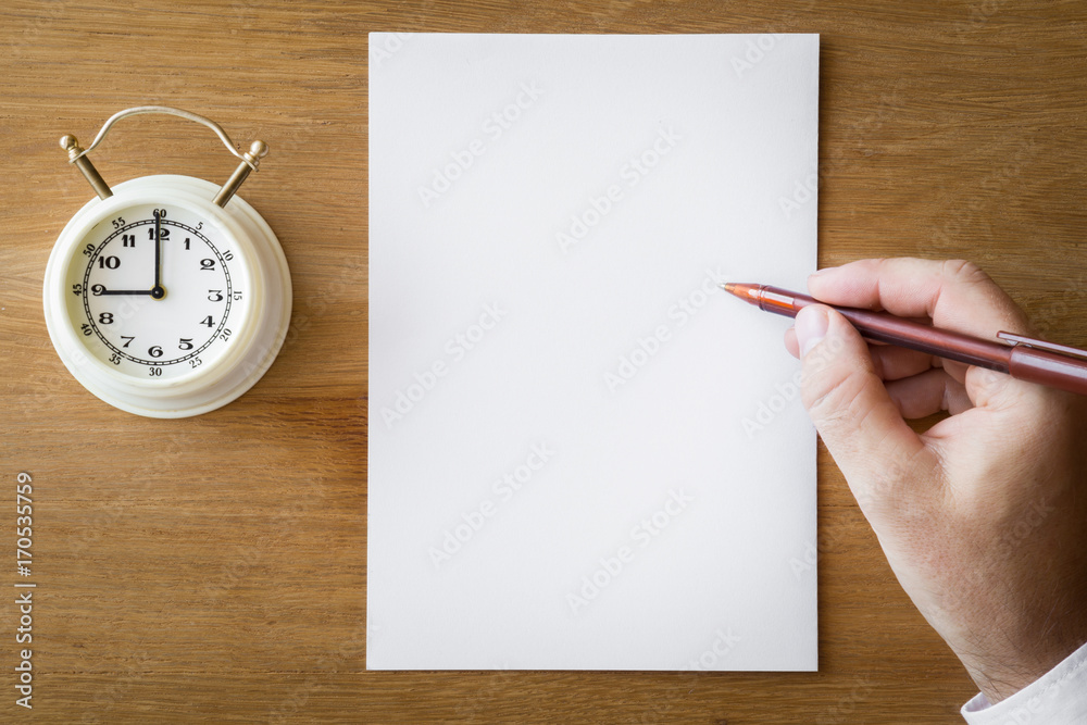 Man's hand writing something with pen. White paper and clock on the wooden  table. Examination time. Education concept. Top view. Empty place for a  text. Stock Photo | Adobe Stock