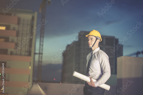 Smiling young architect or engineering builder in hard hat with tablet over group of builders at construction site, architect watching some a construction, business, building, industry, people concept