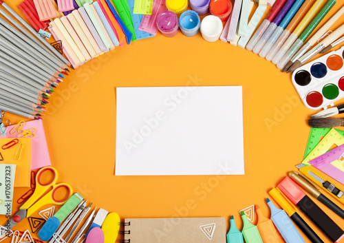 School supplies frame on orange background.
