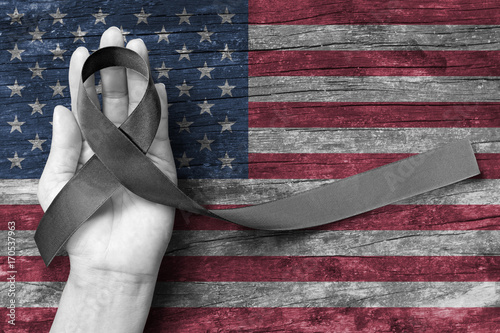 USA United Stated of America 9/11 memorial, Patriot day and National POW/MIA recognition day concept with Black awareness ribbon on people's hand support on American flag photo