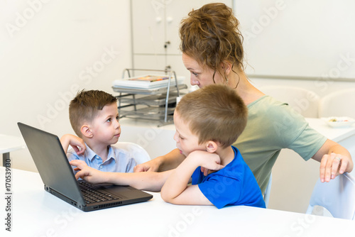 teacher woman learn to use laptop two preschooler boy in the classroom