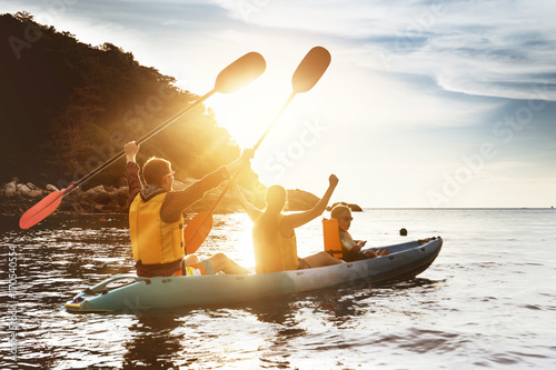 Happy family kayaking sunset sea