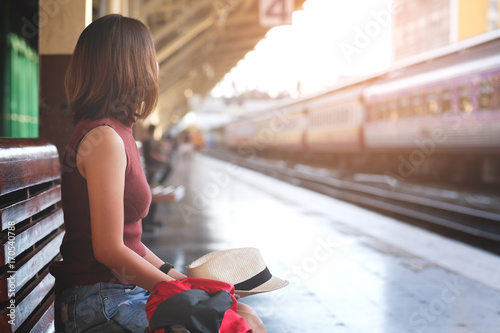 Traveler with backpack waiting for a train at train station. Travel and vacation concept.