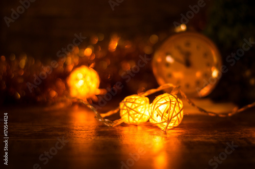 Rattan balls garland on a wooden surface on the background of the clock in the gold toning. Christmas background