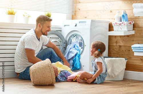 Happy family man father householder and child   in laundry with washing machine photo