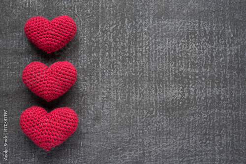 Crocheted red hearts on a grunge board