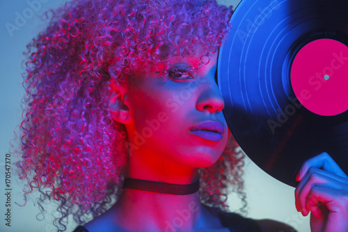 Tableau sur toile portrait of a disco woman holding a vinyl with eighties music and neon light