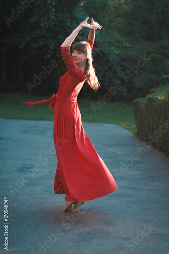 Beautiful young girl in a red long dress dancing. photo