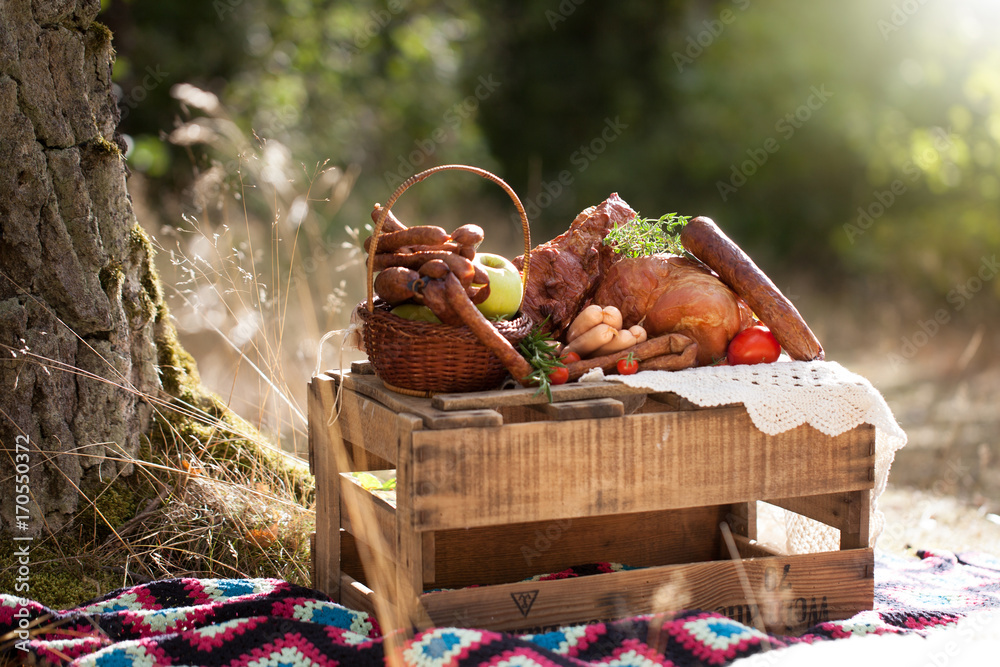 picnic - cured meat, sausages in a basket on the blanket