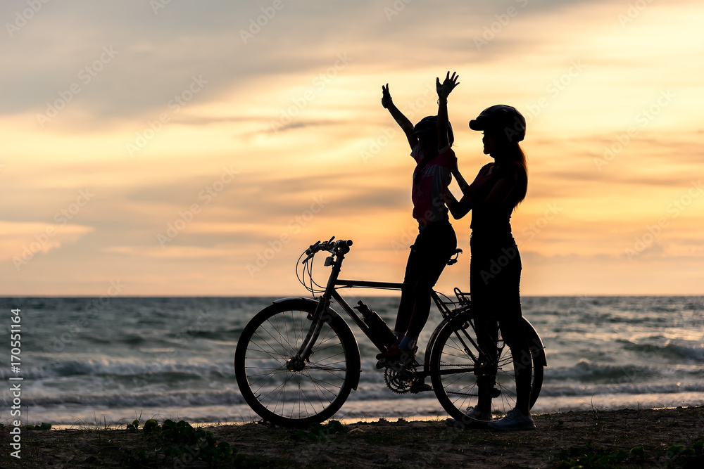 Biker family silhouette at the beach at sunset..