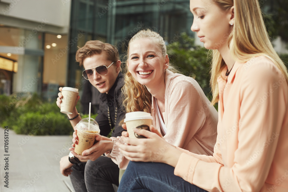 Young adult student people outside in the city drinking coffee and chatting together