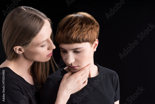 Young woman holding girlfriend by chin
