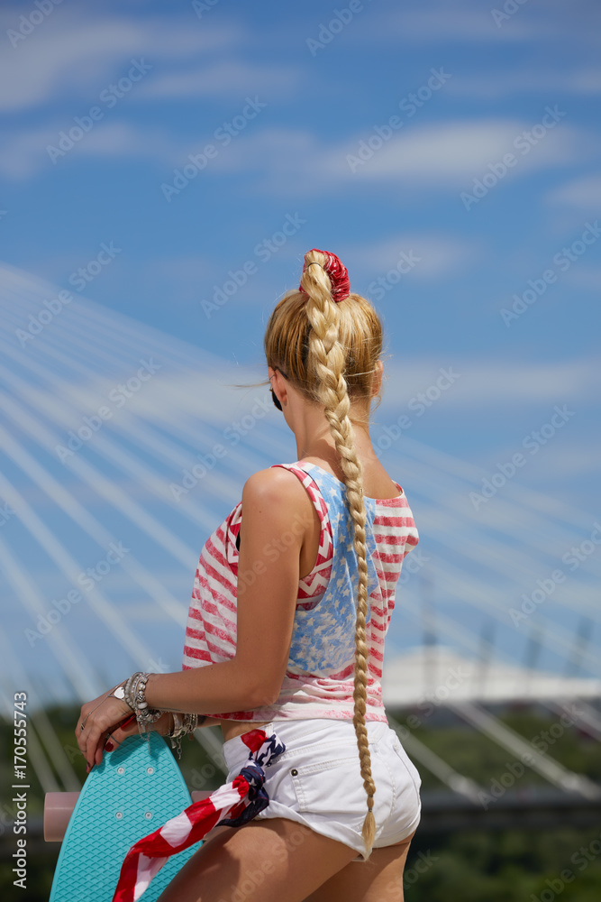 Casual blond female in denim shirt posing on stairs with longboard Casual blond female in denim shirt posing on stairs with longboard