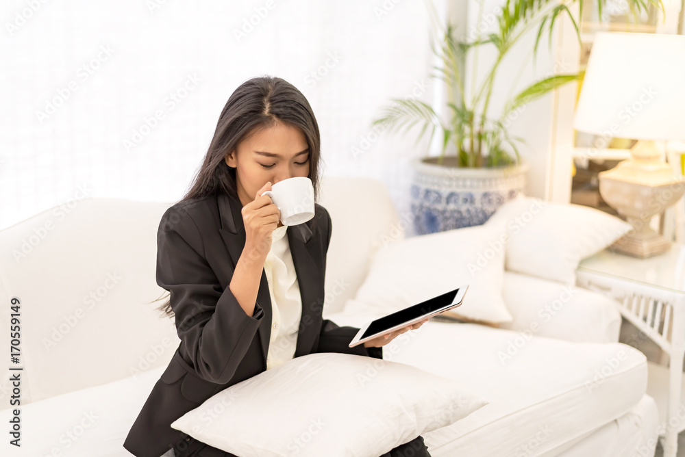 Young businesswoman drinking coffee and using tablet computer in home ,morning time Young businesswoman drinking coffee and using tablet computer in home ,morning time