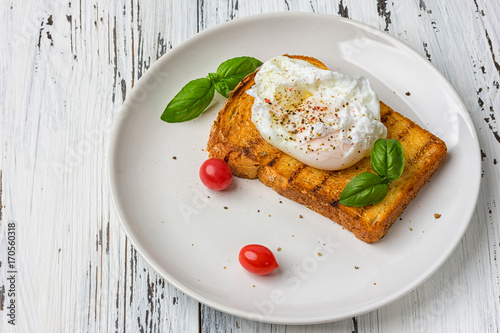 Poached egg on a piece of bread on the wooden table