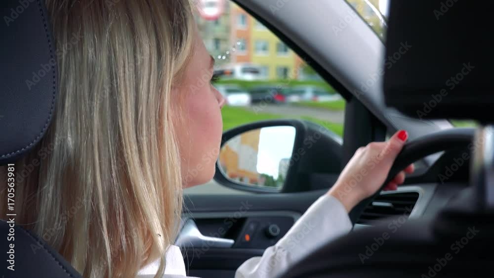 Young attractive blond woman drives a car in rainy day - road in the city - closeup Young attractive blond woman drives a car in rainy day - road in the city - closeup