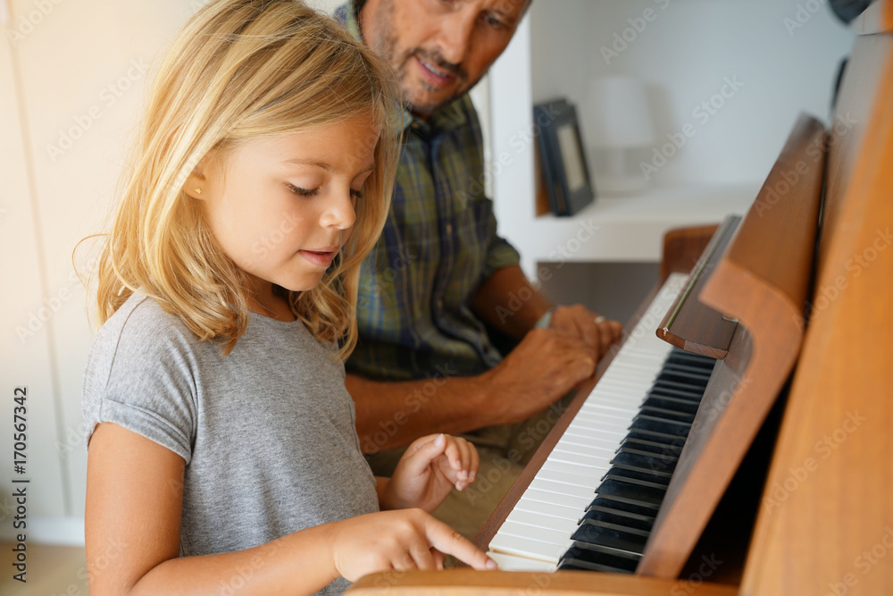 Fototapeta Little girl with teacher playing piano