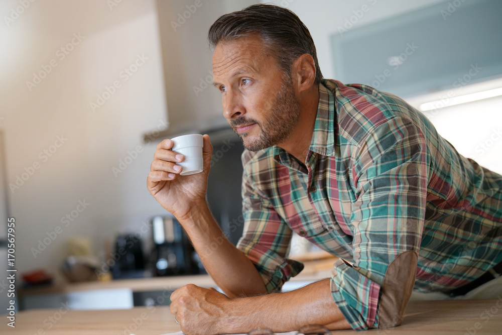 Mature man drinking coffee in home kitchen Mature man drinking coffee in home kitchen