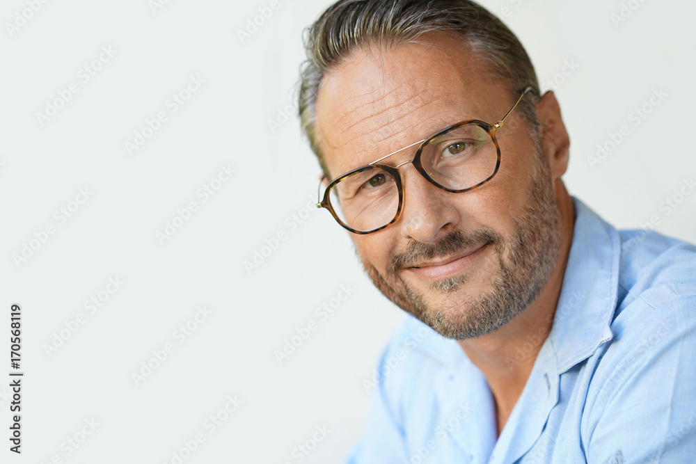 Portrait of mature man with eyeglasses and blue shirt, isolated