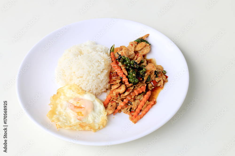 stir fried chicken with roasted chili paste and fresh Piper nigrum on jasmine rice in white plate on white background. Thai style food.