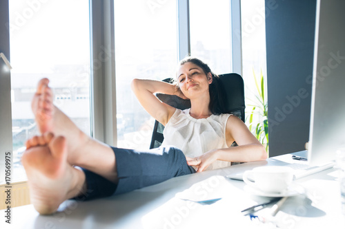 Фотография Businesswoman in her office sitting with legs on desk.