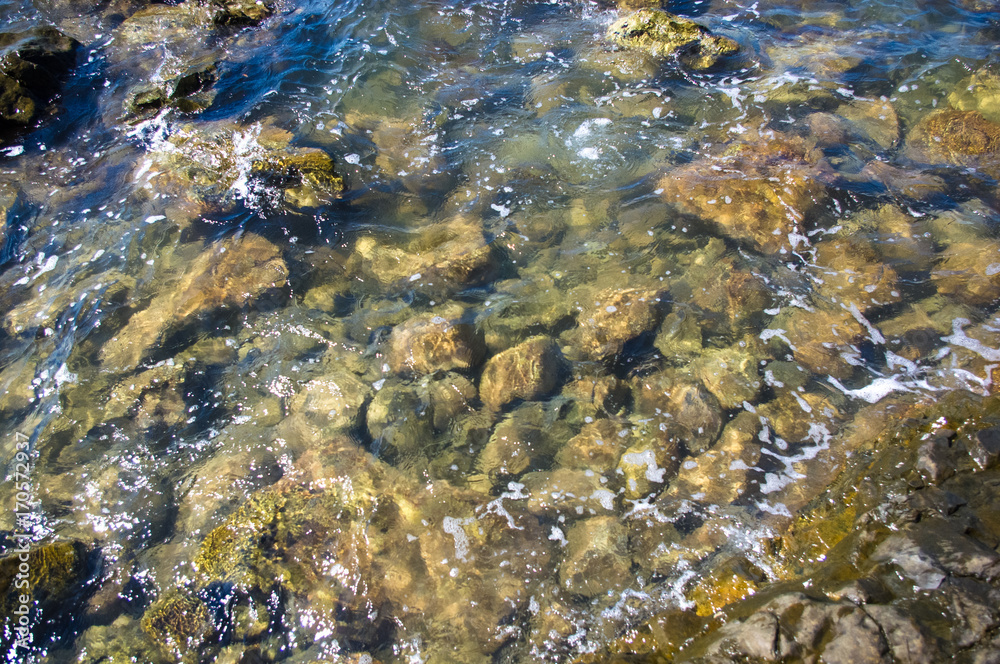 rocky sea shore with pebble beach, waves with foam